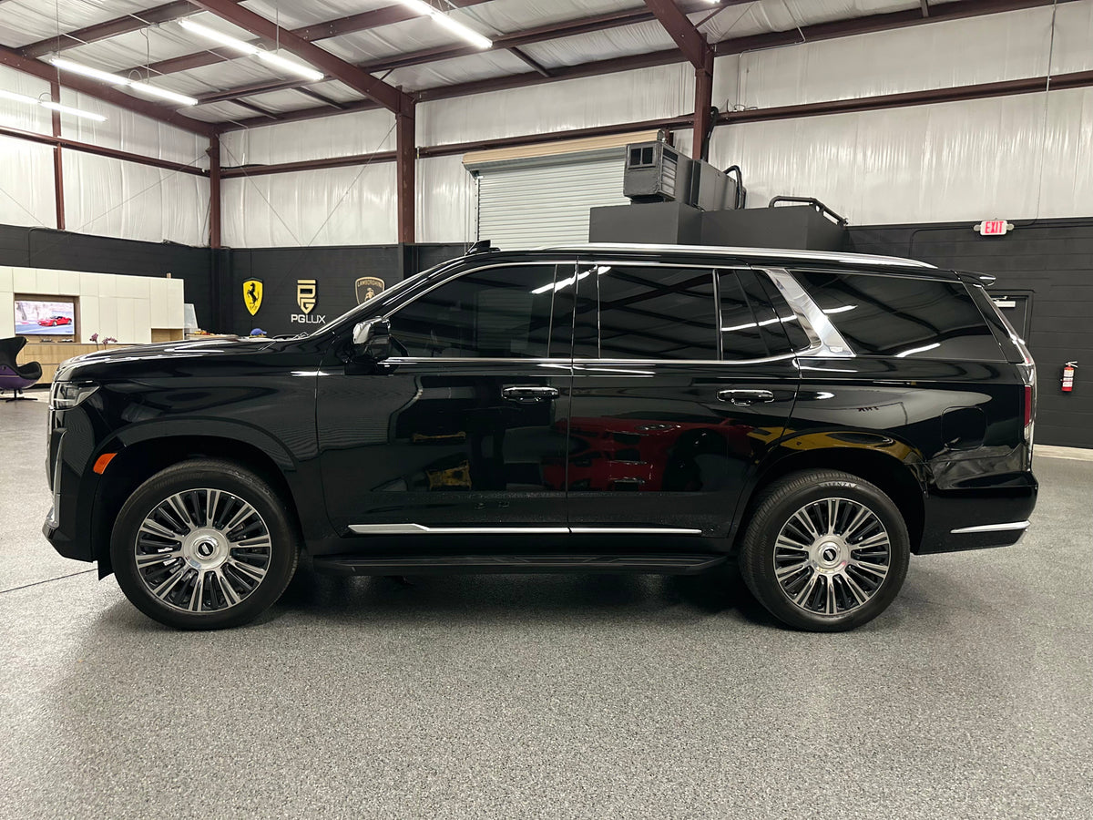 Black luxury full-size SUV with tinted windows and alloy wheels parked inside a showroom, premium family vehicle, modern spacious design.